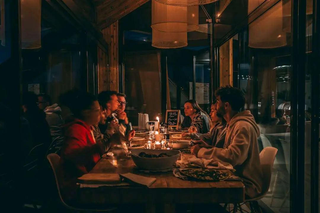 Persone a cena a un lungo tavolo di legno