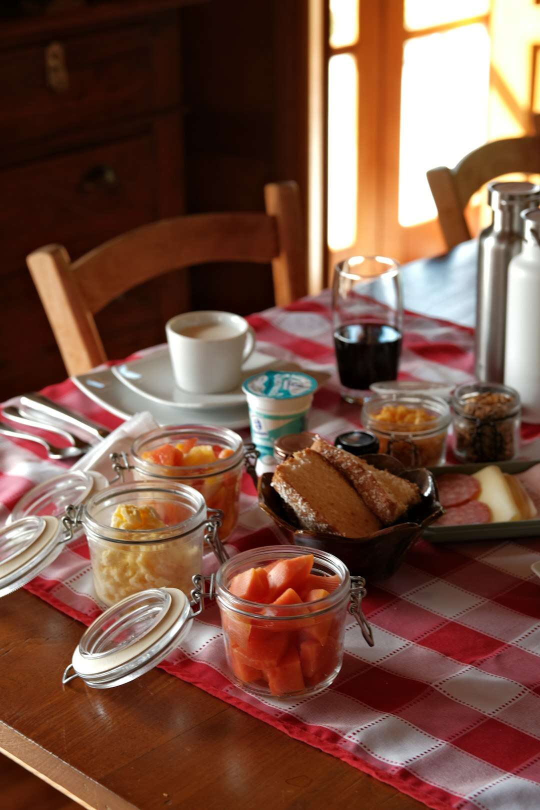 Tavola della colazione con frutta, yogurt, pane e conserve alla luce del mattino